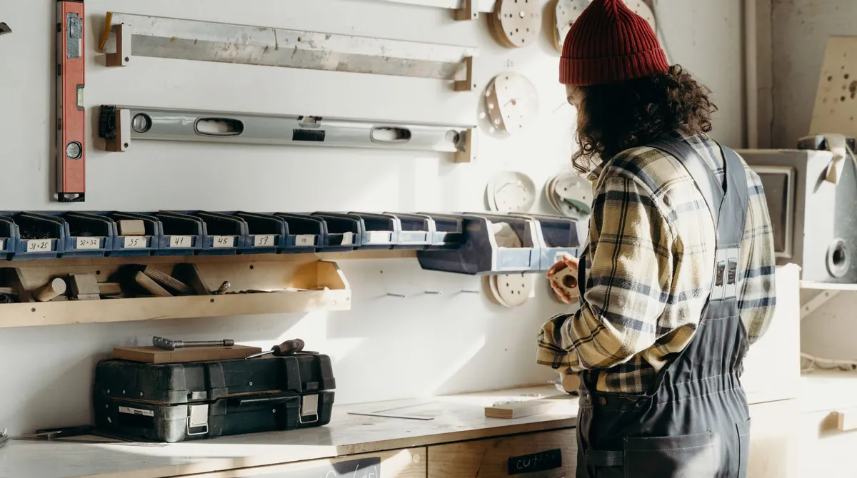 Artisan menuisier de dos dans son atelier devant un mur d'outils, agence web fermée et site bloqué