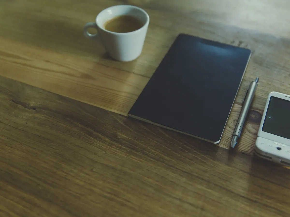 Carnet ouvert et stylo sur un bureau en bois, pour noter qui possède quoi sur son site
