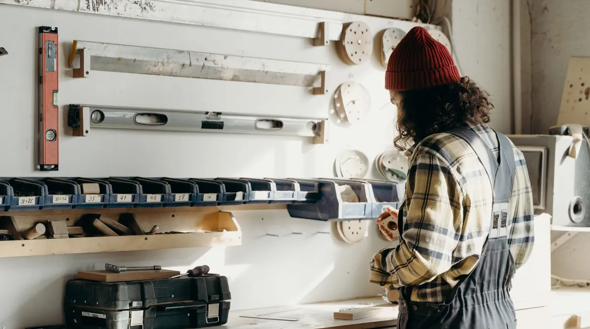 Artisan de dos dans son atelier de menuiserie, outils rangés au mur, lumière chaude : surveiller sa réputation en ligne
